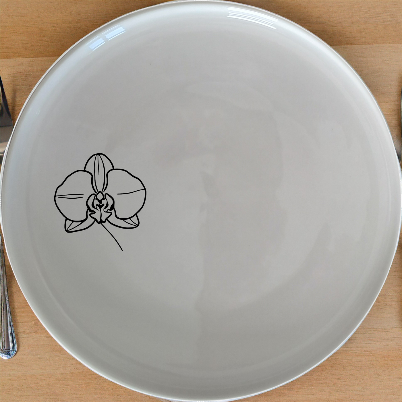 The Orchid Side Plate Set 3 features a delicate laser-etched orchid design on a smooth white ceramic surface, perfect for adding a touch of sophistication to any meal.