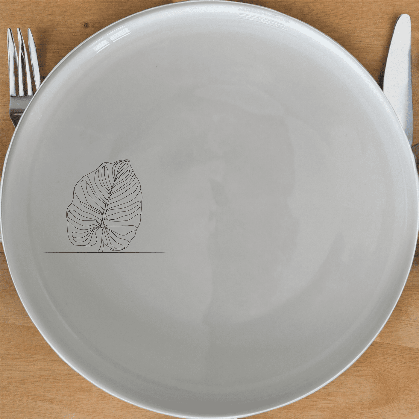 The Calathea Orbifolia Dinner Plate Set of 4 features a minimalist design with a subtle leaf motif, perfect for modern dining settings.