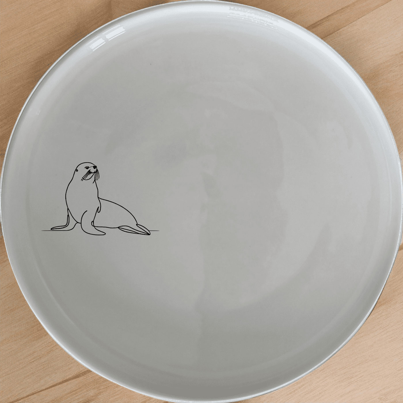 The Cape Fur Seal Dinner Plate Set of 4 features elegant silhouettes on white ceramic plates, perfect for modern dining.