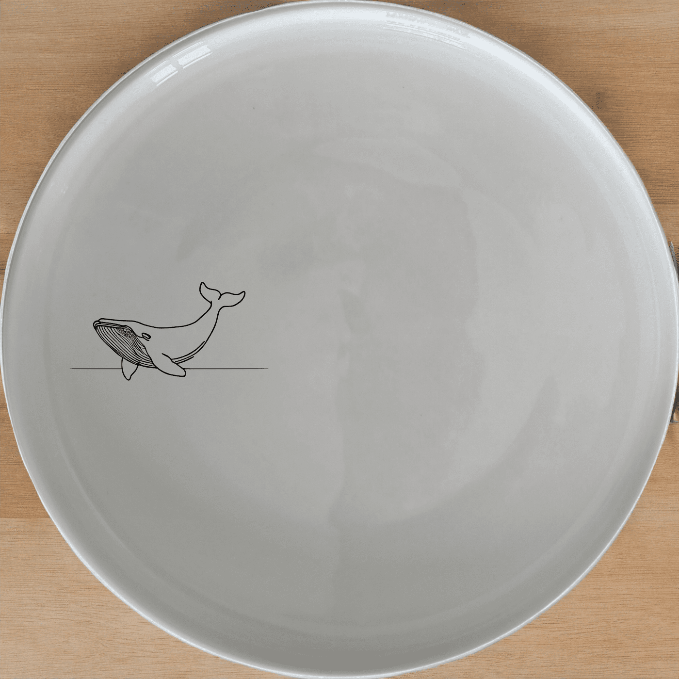 The Floating Breaching Whale Dinner Plate Set of 4 features a minimalist silhouette design, perfect for modern dining settings.