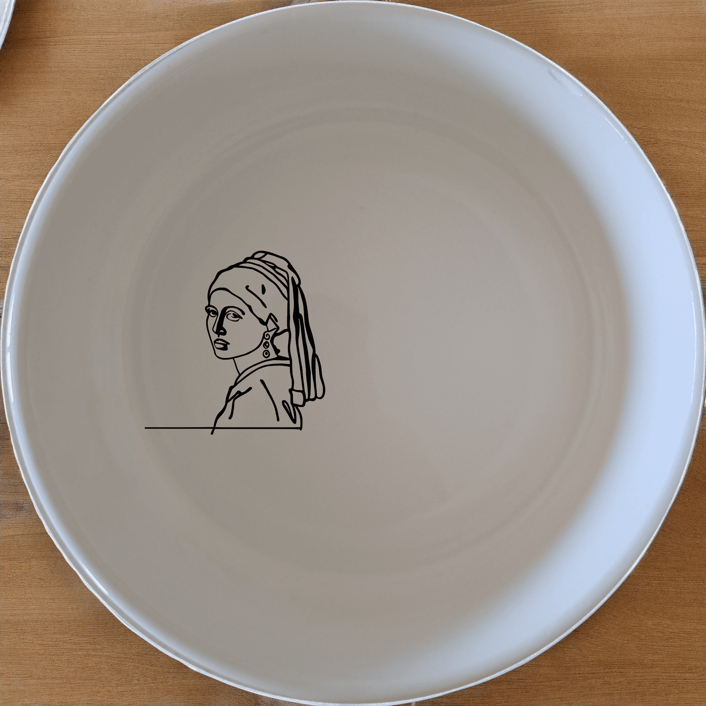 The Girl Pearl Earring Bowl Set of 4 features a minimalist design with a subtle artistic touch, perfect for everyday use or special occasions.