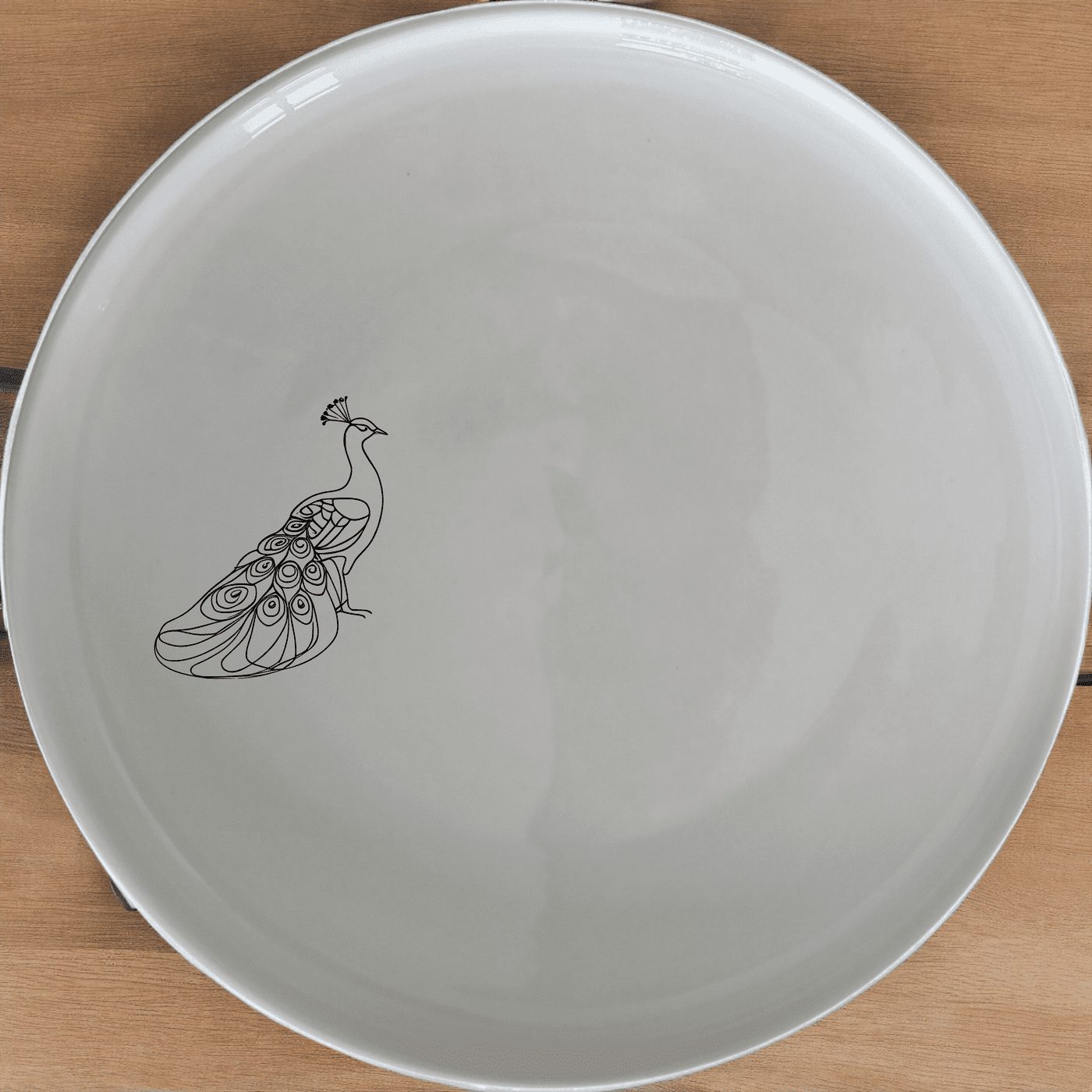 The Male Peacock Side Plate Set of 4 features an elegant design perfect for any dining table. This set includes four white ceramic plates with a subtle peacock motif, ideal for both everyday use and special occasions.