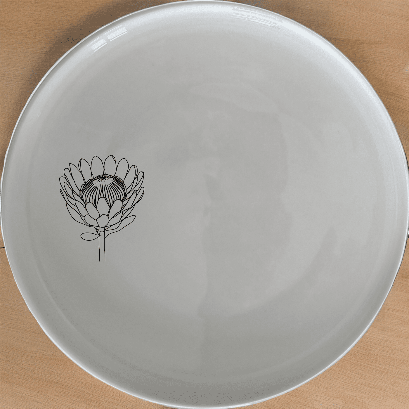 The Pincushion Protea Flower Side Plate Set of 4 features a beautiful laser-etched design on a sleek white ceramic surface, perfect for any dining occasion.