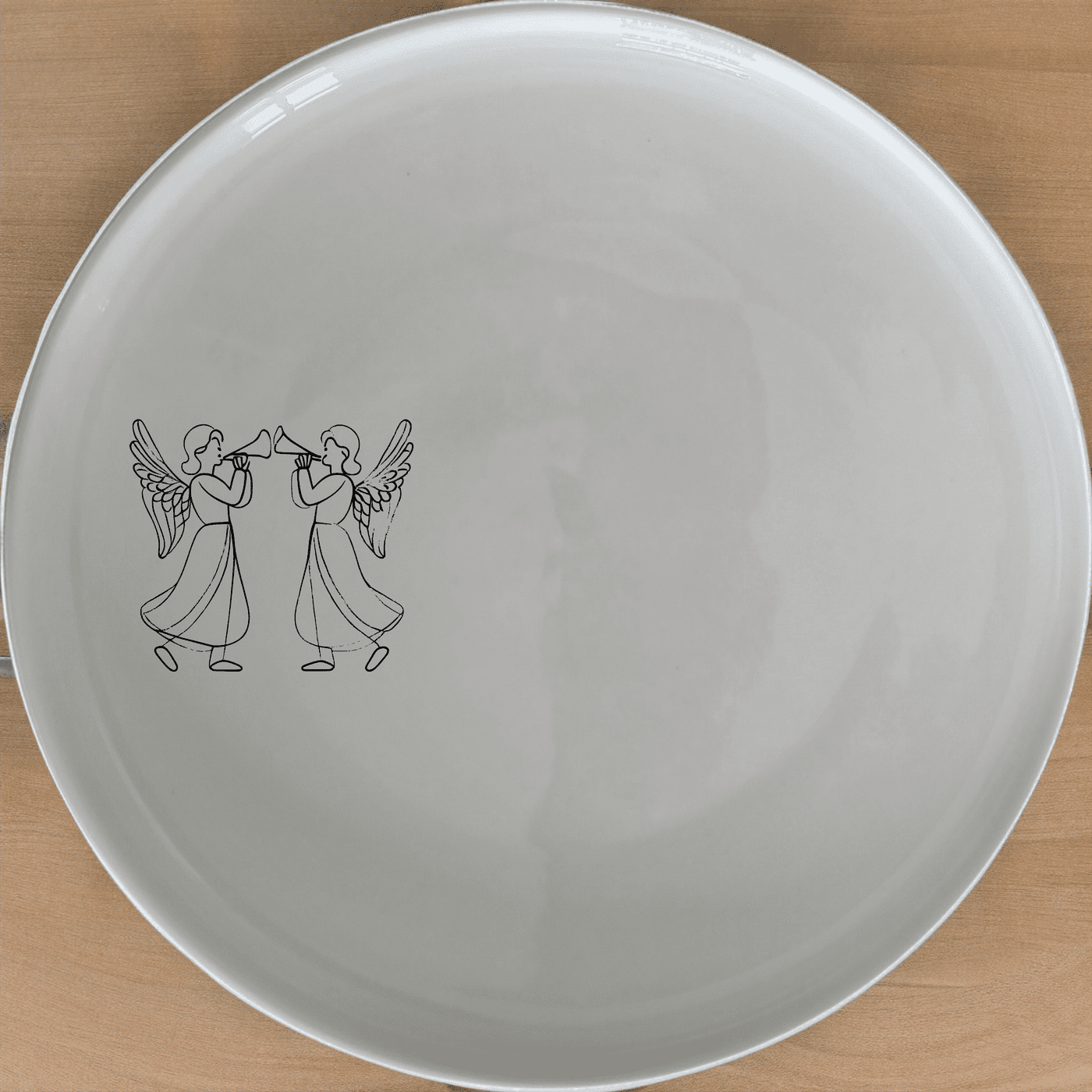 Angels Trumpet Side Plate Set of 4 - Range 1 is a beautiful and elegant set of four white ceramic side plates, each featuring a laser-etched design of two angels playing trumpets. Perfect for adding a touch of celestial charm to your dining table.