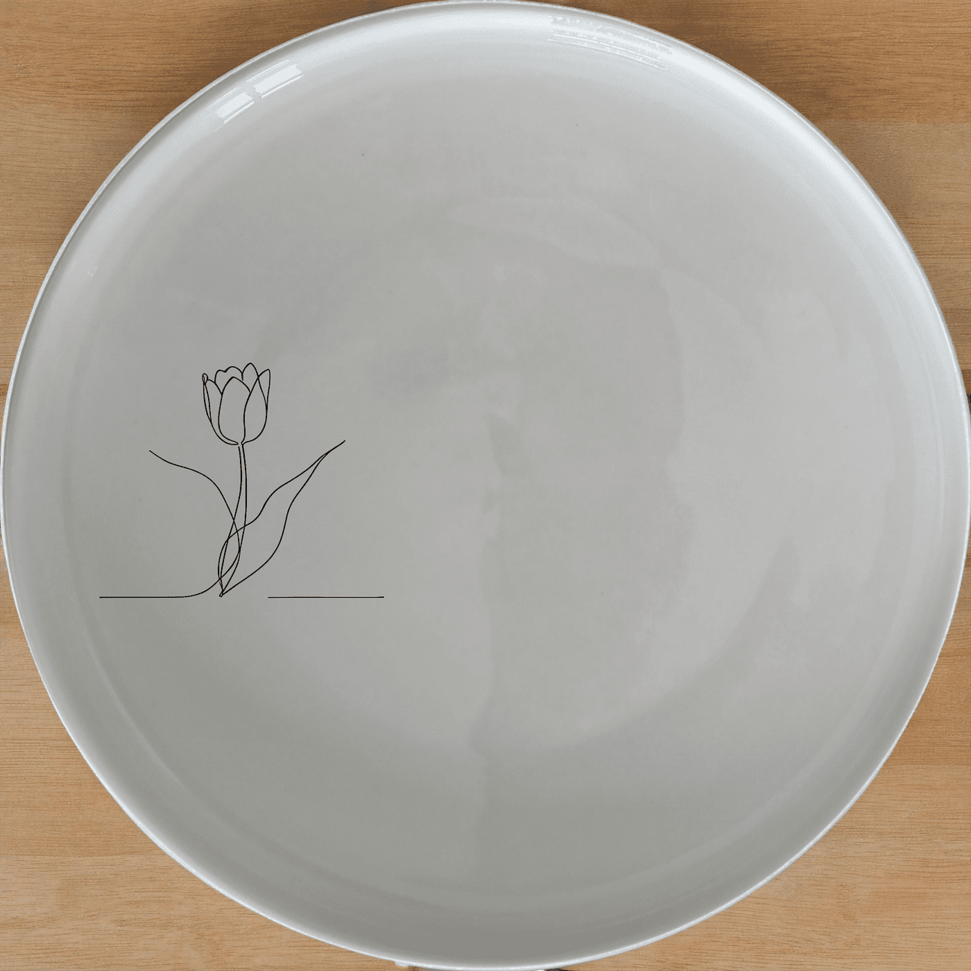 The Tulips Side Plate Set of 4 features a minimalist design with a single tulip illustration, perfect for adding a touch of nature to your dining table.